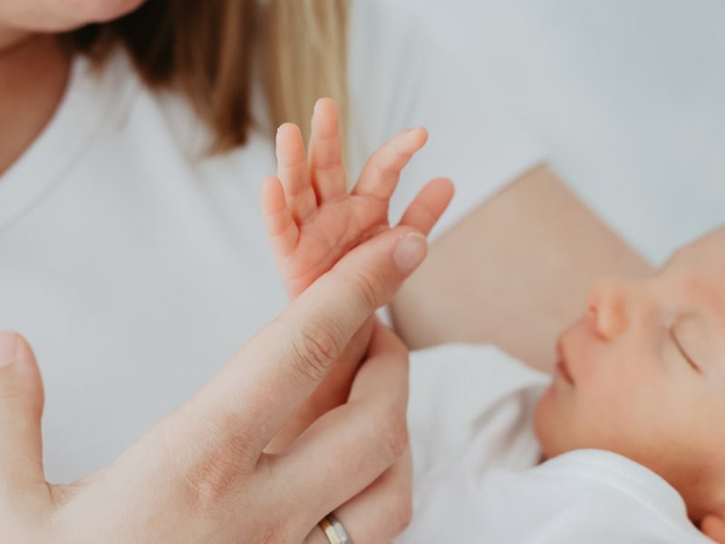 Hand eines Neugeborenen, die von einer Erwachsenenhand berührt wird