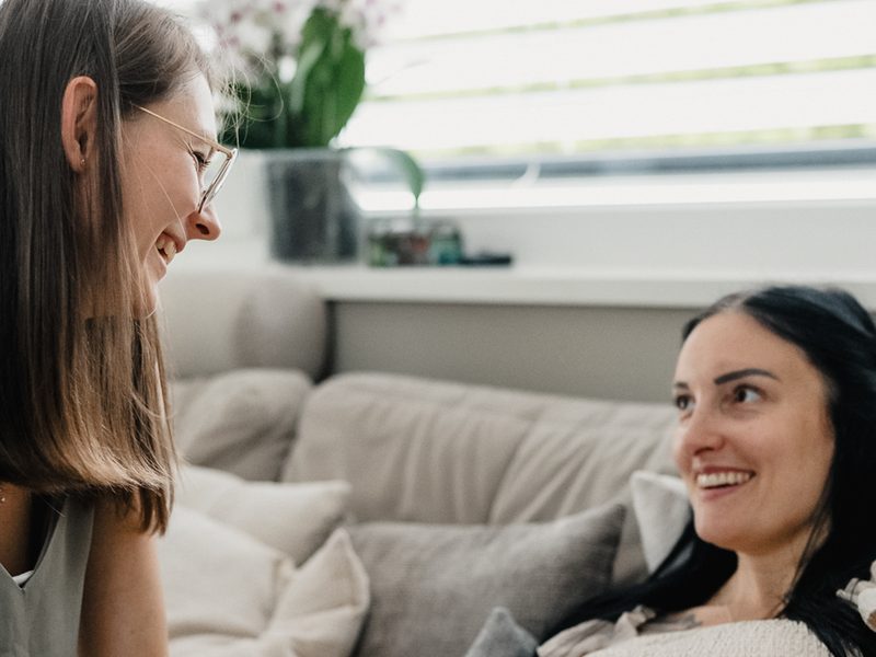 Zwei Frauen lachen miteinander auf dem Sofa